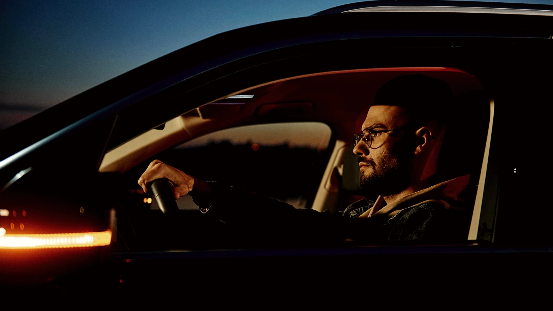 Mann ab 40 sitzt in der Abenddämmerung im Auto und erlebt einen stillen Moment der Erkenntnis und Selbstreflexion